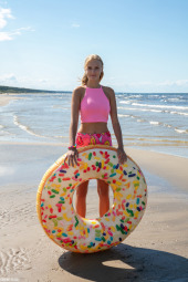 Remarkable young blonde girl on the beach seaside in pink shorts and pink top showing her sexy fresh body